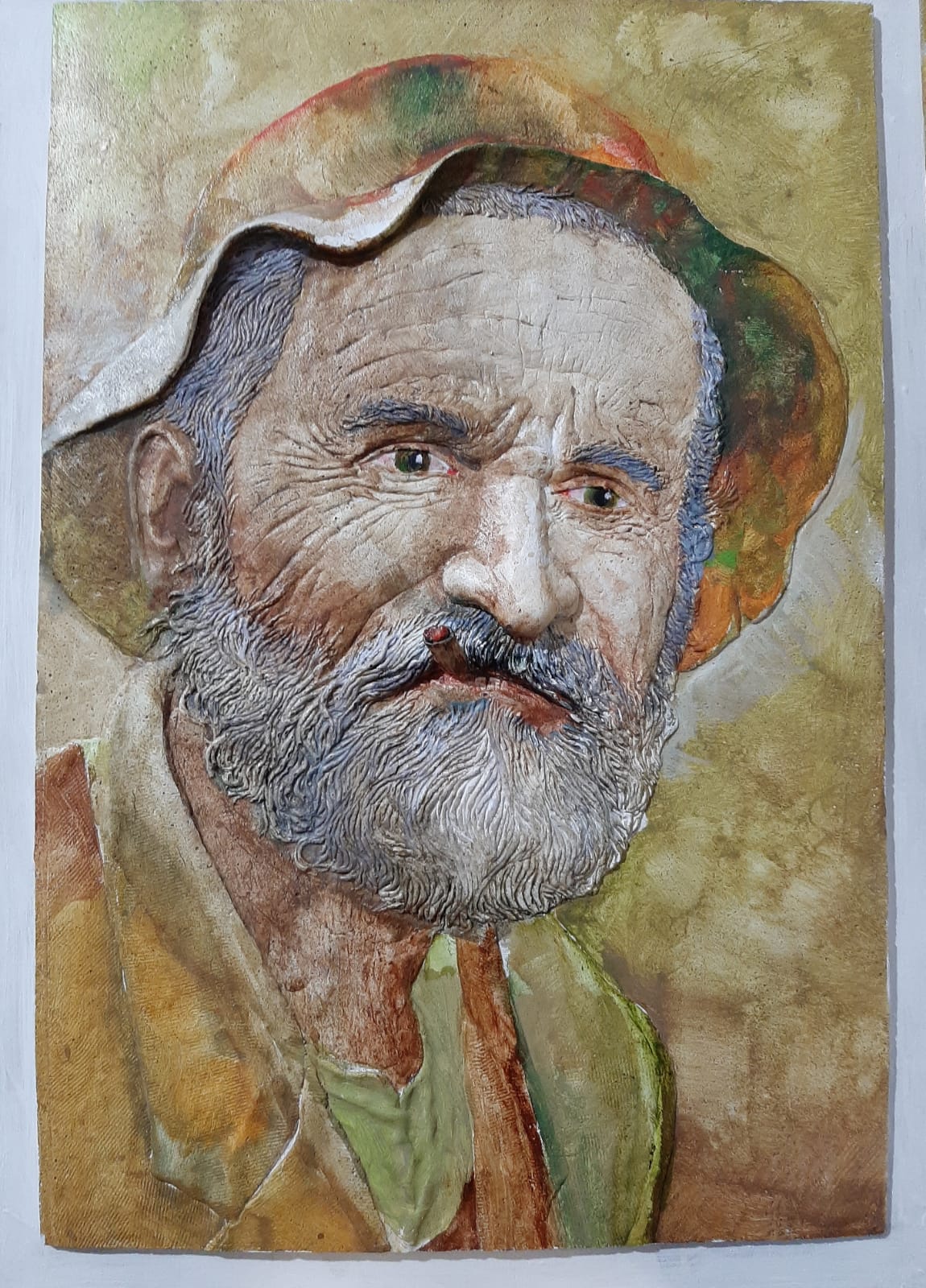 Igrejinha: um senhor saudável com roupa e chapéu amarelo fuma um cigarro. Pintura em acrílico sobre baixo relevo